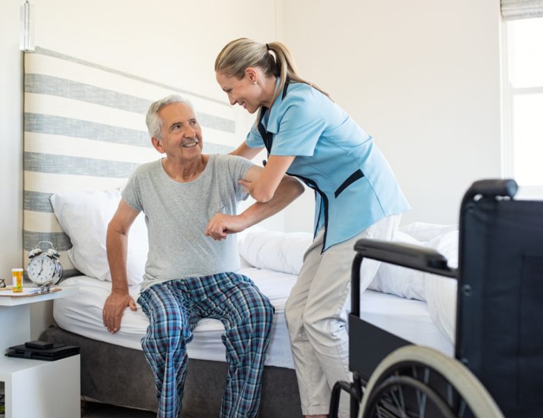 Nurse helping senior out of bed